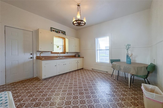 kitchen featuring a notable chandelier, sink, white cabinetry, and hanging light fixtures