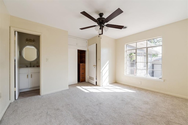 unfurnished bedroom featuring ceiling fan, a closet, light colored carpet, and ensuite bath