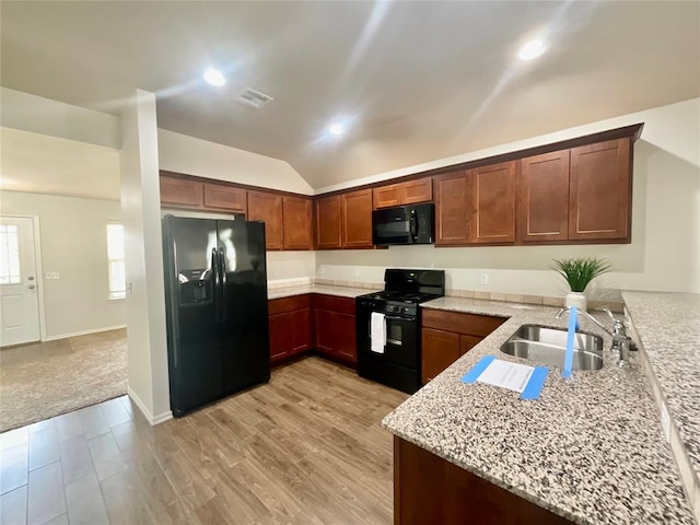 kitchen featuring light stone countertops, sink, light hardwood / wood-style floors, vaulted ceiling, and black appliances