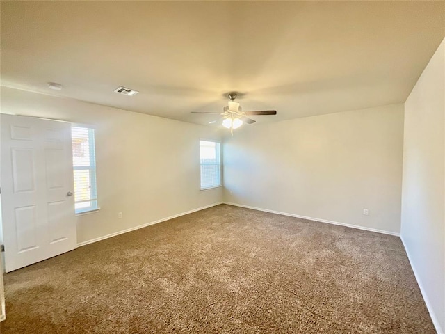 empty room with ceiling fan and dark carpet