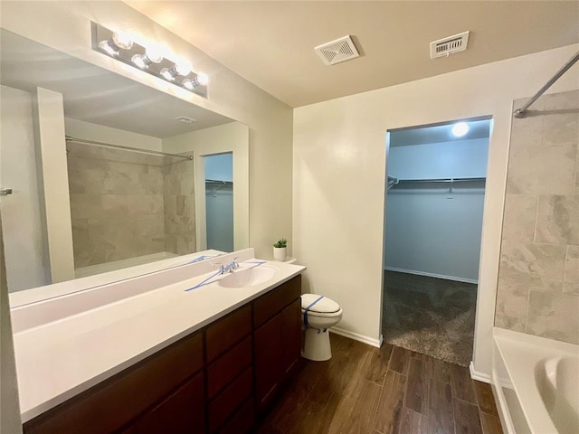 full bathroom featuring vanity, wood-type flooring, tiled shower / bath combo, and toilet