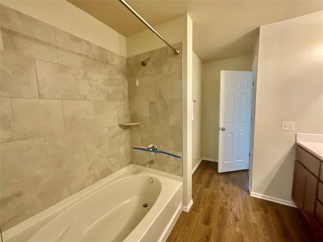 bathroom featuring wood-type flooring, vanity, vaulted ceiling, and tiled shower / bath