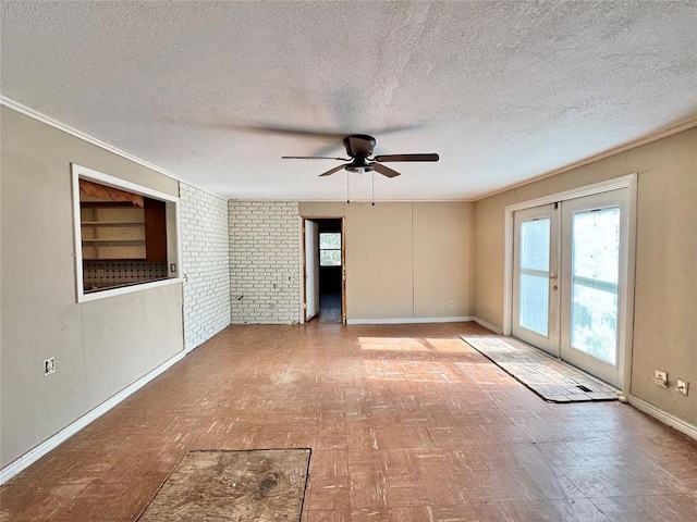 empty room featuring french doors, built in shelves, ceiling fan, a textured ceiling, and brick wall