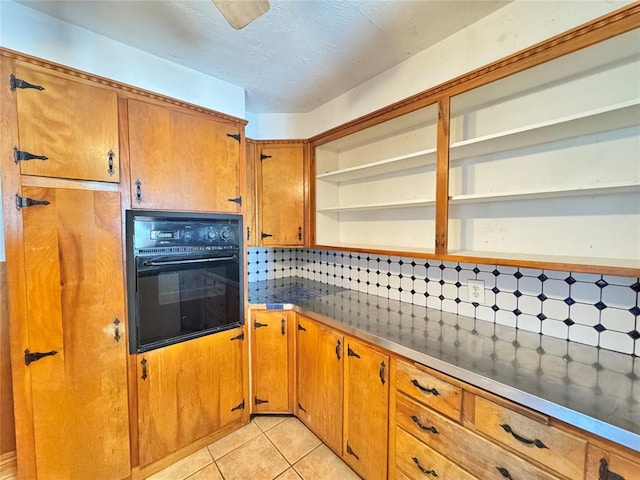 kitchen featuring tasteful backsplash, black oven, and light tile patterned floors