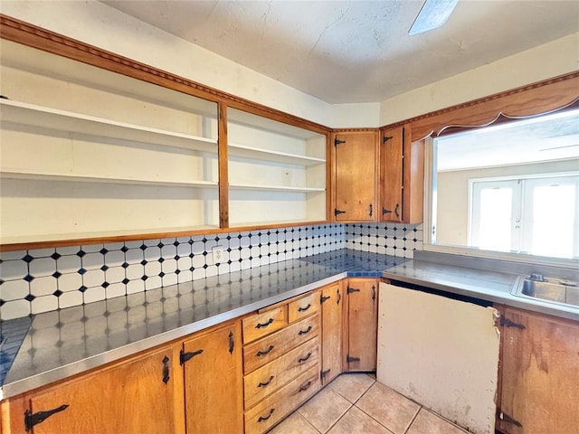 kitchen featuring stainless steel counters, light tile patterned floors, sink, and tasteful backsplash