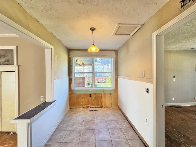 interior space featuring wood walls, light tile patterned floors, and a textured ceiling