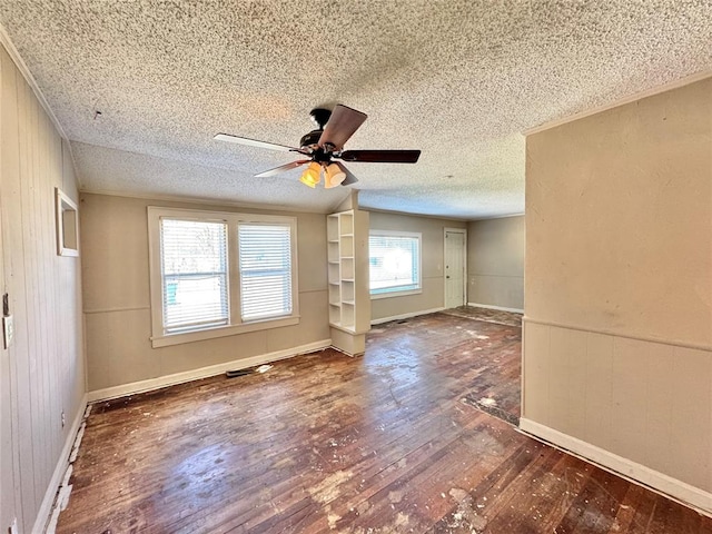 interior space with ceiling fan, dark hardwood / wood-style flooring, wood walls, and a textured ceiling