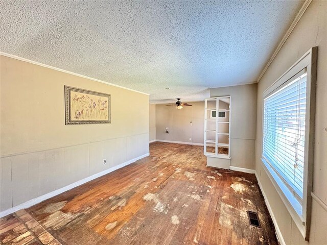 empty room featuring ceiling fan, ornamental molding, a textured ceiling, and hardwood / wood-style flooring