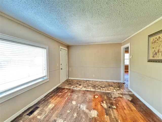 unfurnished room with a textured ceiling, dark hardwood / wood-style flooring, and ornamental molding