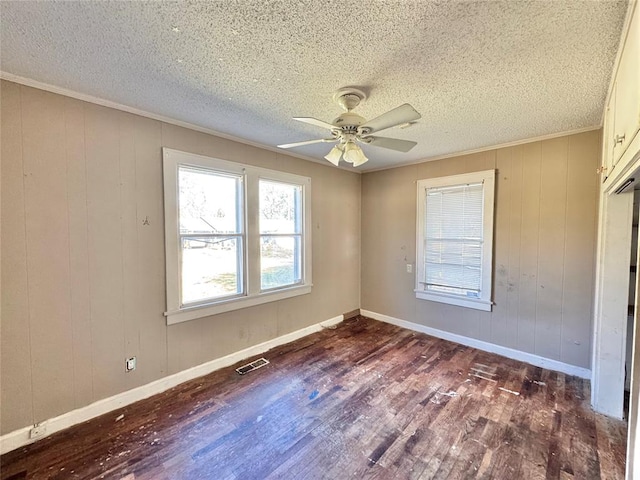 unfurnished room featuring a textured ceiling, ceiling fan, dark wood-type flooring, and wood walls