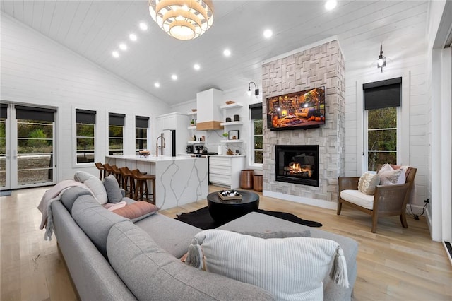 living room with light wood-type flooring, sink, high vaulted ceiling, wooden ceiling, and a fireplace