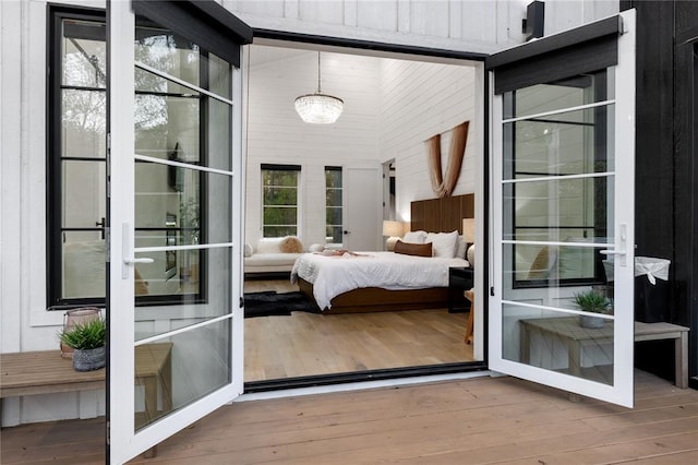 bedroom featuring a chandelier, hardwood / wood-style floors, high vaulted ceiling, and wooden walls