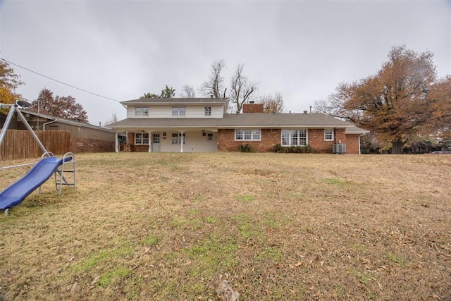 back of property with a playground, a lawn, and cooling unit