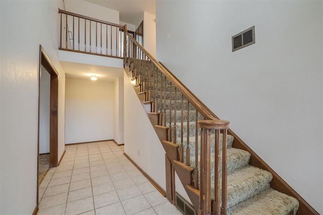 stairway featuring tile patterned flooring and a high ceiling