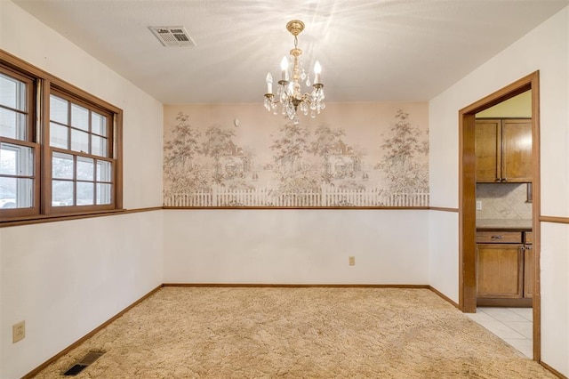 empty room featuring light carpet and a notable chandelier