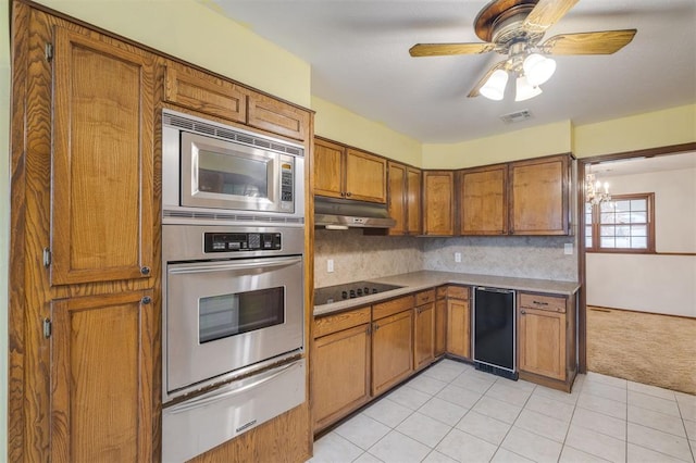 kitchen with ceiling fan with notable chandelier, light tile patterned floors, decorative backsplash, and appliances with stainless steel finishes