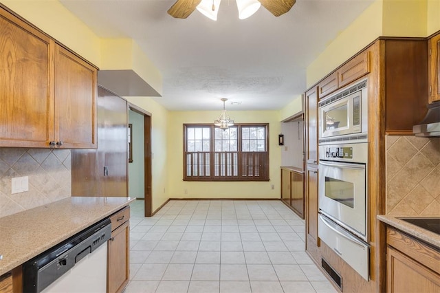 kitchen with backsplash, pendant lighting, ceiling fan with notable chandelier, and appliances with stainless steel finishes