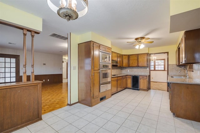 kitchen featuring wood walls, sink, ceiling fan, appliances with stainless steel finishes, and light parquet flooring