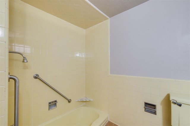 bathroom with tile walls and tiled shower / bath