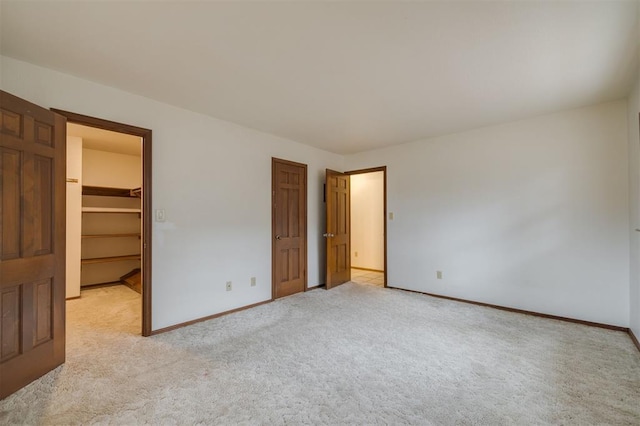 unfurnished bedroom with light colored carpet, a spacious closet, and a closet