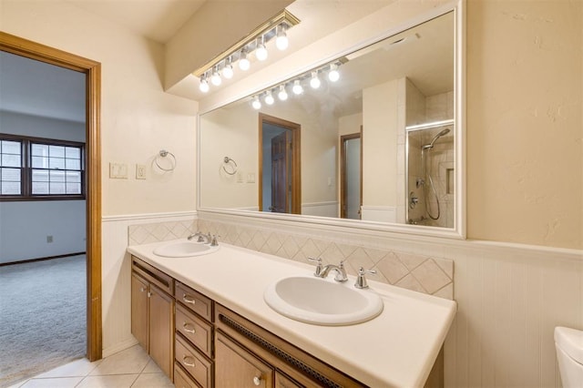 bathroom with tile patterned flooring, vanity, toilet, and tiled shower