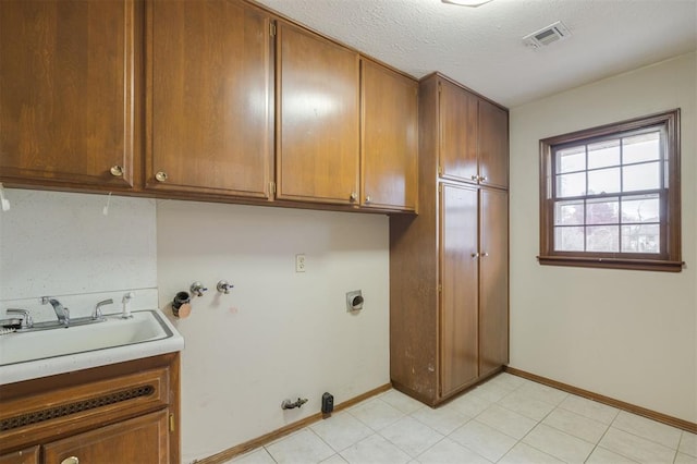 clothes washing area with sink, cabinets, electric dryer hookup, gas dryer hookup, and a textured ceiling