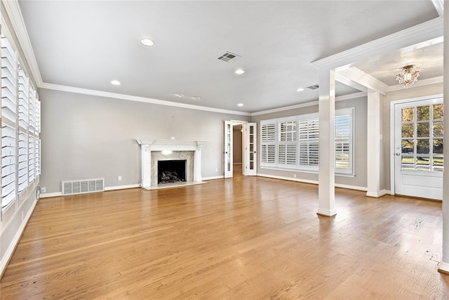 unfurnished living room with crown molding, a fireplace, a notable chandelier, and light wood-type flooring