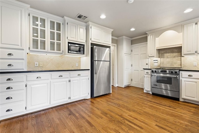 kitchen with white cabinets, appliances with stainless steel finishes, and hardwood / wood-style flooring