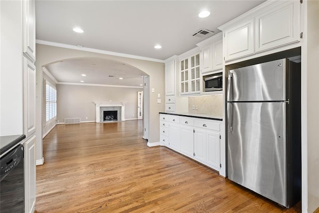 kitchen featuring white cabinetry, stainless steel appliances, light hardwood / wood-style floors, a fireplace, and ornamental molding