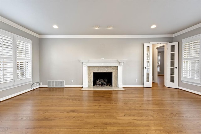 unfurnished living room featuring a fireplace, wood-type flooring, and ornamental molding