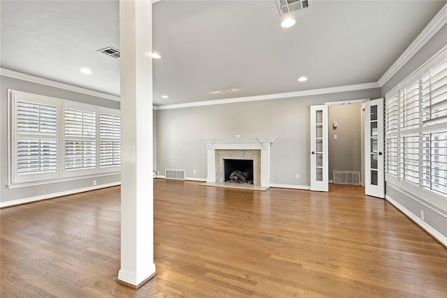 unfurnished living room featuring a high end fireplace, wood-type flooring, and ornamental molding