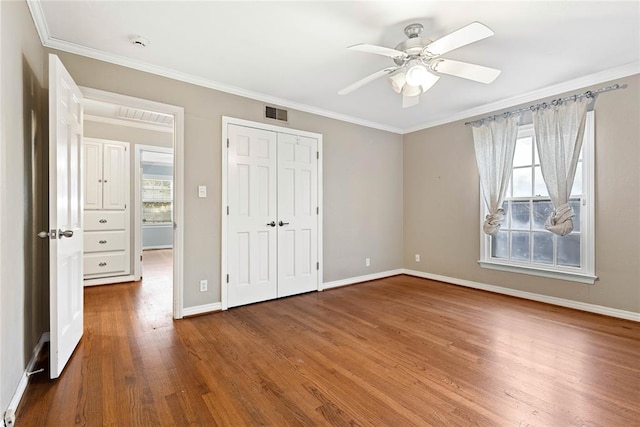 unfurnished bedroom featuring ceiling fan, a closet, wood-type flooring, and ornamental molding