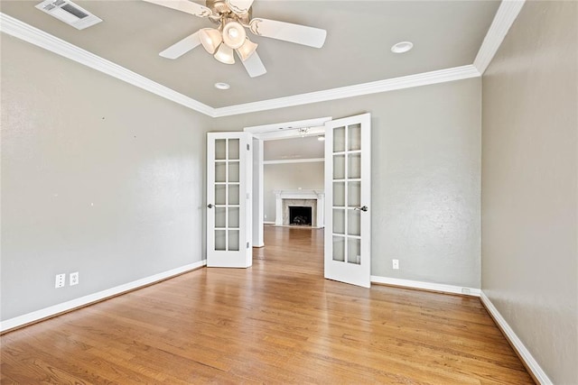 empty room featuring french doors, light wood-type flooring, ceiling fan, and ornamental molding