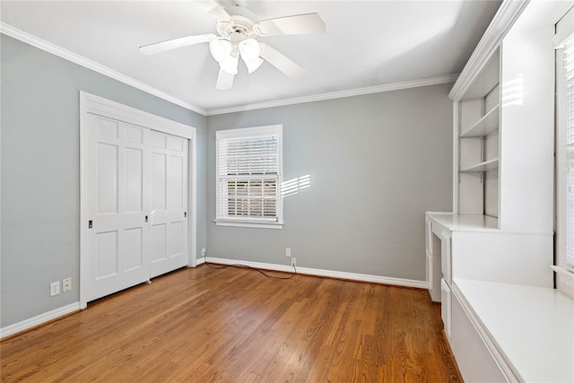 unfurnished bedroom with ceiling fan, wood-type flooring, crown molding, and a closet