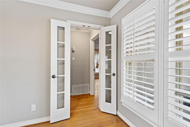 doorway featuring light wood-type flooring, ornamental molding, and french doors