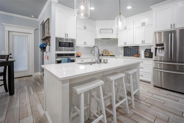 kitchen featuring white cabinets, decorative light fixtures, sink, and appliances with stainless steel finishes