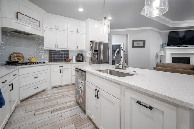 kitchen with white cabinets, sink, hanging light fixtures, ornamental molding, and stainless steel appliances