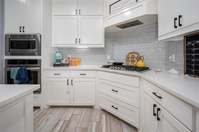 kitchen featuring white cabinets, appliances with stainless steel finishes, and light stone countertops