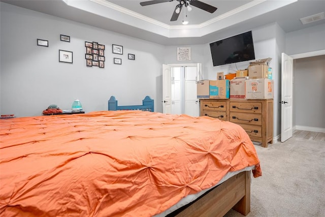 bedroom featuring light carpet, a tray ceiling, ceiling fan, and crown molding