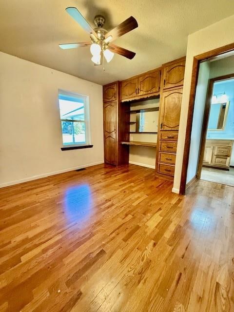 interior space featuring ceiling fan, built in desk, and light hardwood / wood-style flooring