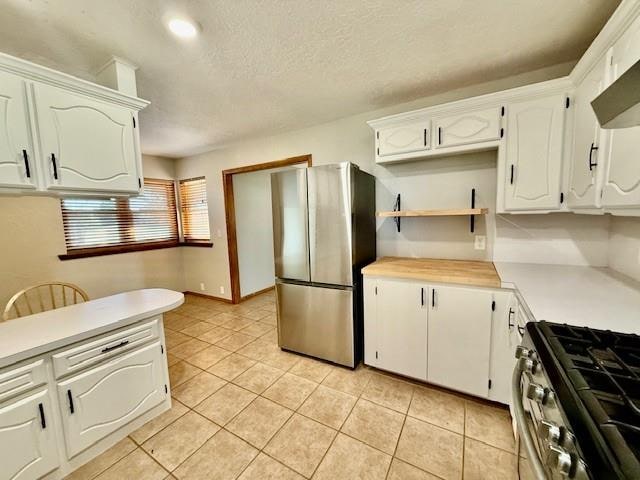 kitchen featuring white cabinets, appliances with stainless steel finishes, light tile patterned floors, and range hood