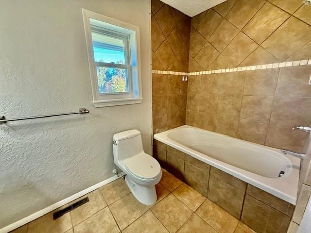 bathroom featuring tile patterned flooring, tiled shower / bath combo, and toilet