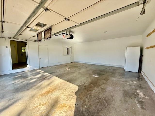 garage featuring white refrigerator, electric panel, and a garage door opener