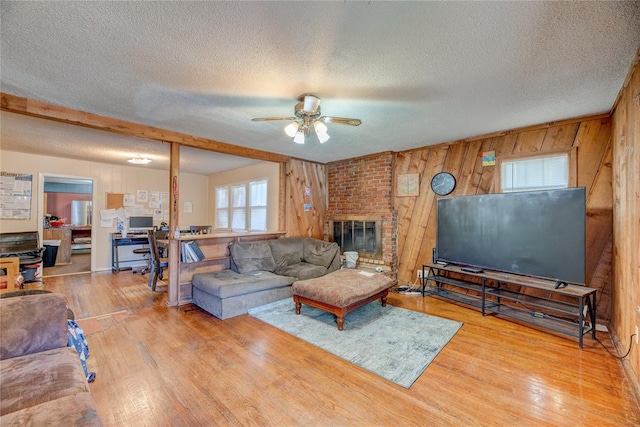 living room with wood walls, ceiling fan, wood-type flooring, and a textured ceiling