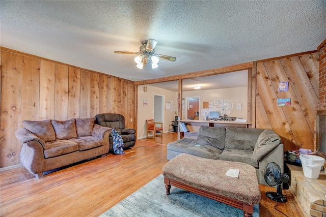 living room with a textured ceiling, hardwood / wood-style flooring, ceiling fan, and wooden walls