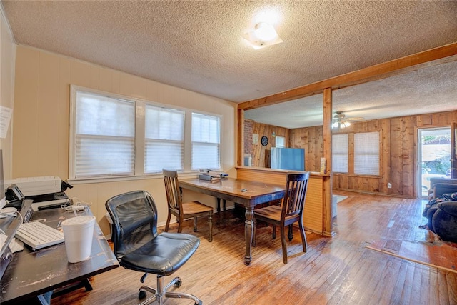 interior space featuring a textured ceiling, hardwood / wood-style flooring, ceiling fan, and wooden walls