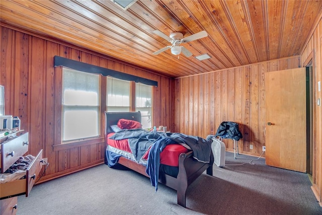 bedroom with ceiling fan, wooden walls, and wood ceiling