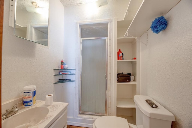 bathroom featuring a shower with door, vanity, and toilet