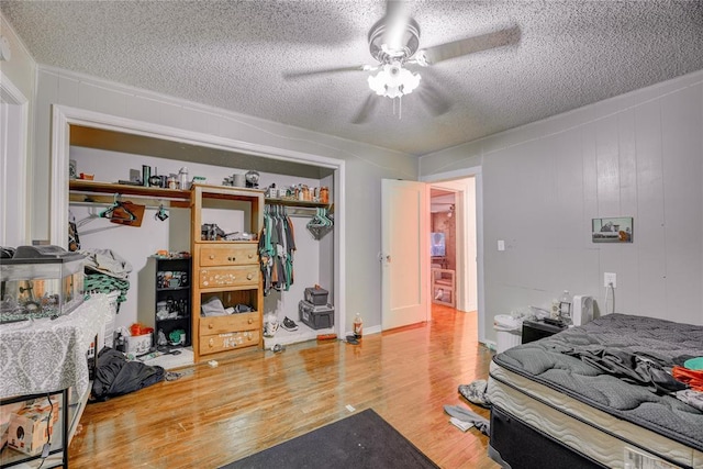 bedroom featuring ceiling fan, a closet, wood-type flooring, and a textured ceiling