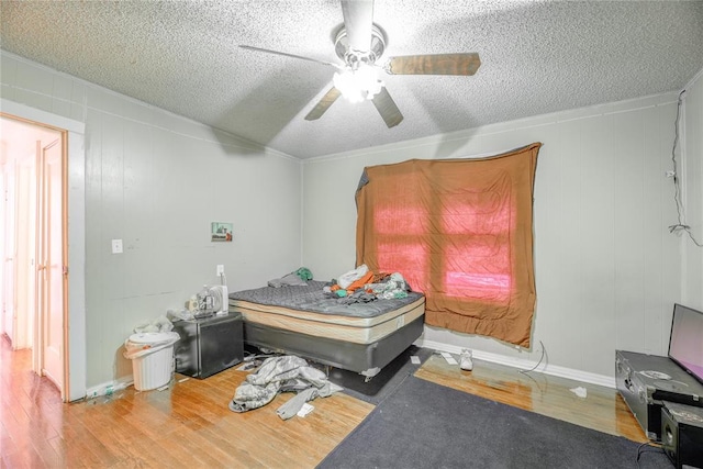 bedroom featuring ceiling fan, crown molding, wood-type flooring, and a textured ceiling